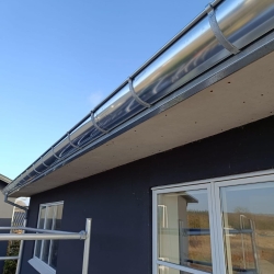 Montering og renovering af blanke stål tagrender på sort hus i Nyborg – professionel opsætning af tagrender i Bogense og resten af Fyn