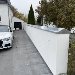 Zinkinddækning på hvid mur ved indkørsel – elegant og funktionel løsning fra Raaschou Blik i Odense, der beskytter muren mod fugt og nedbør